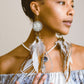 Front view of model wearing Feather Earrings – a statement piece handcrafted with Flower of Life Sacred Geometry, featuring clear quartz, Lapis, pearl & gold.