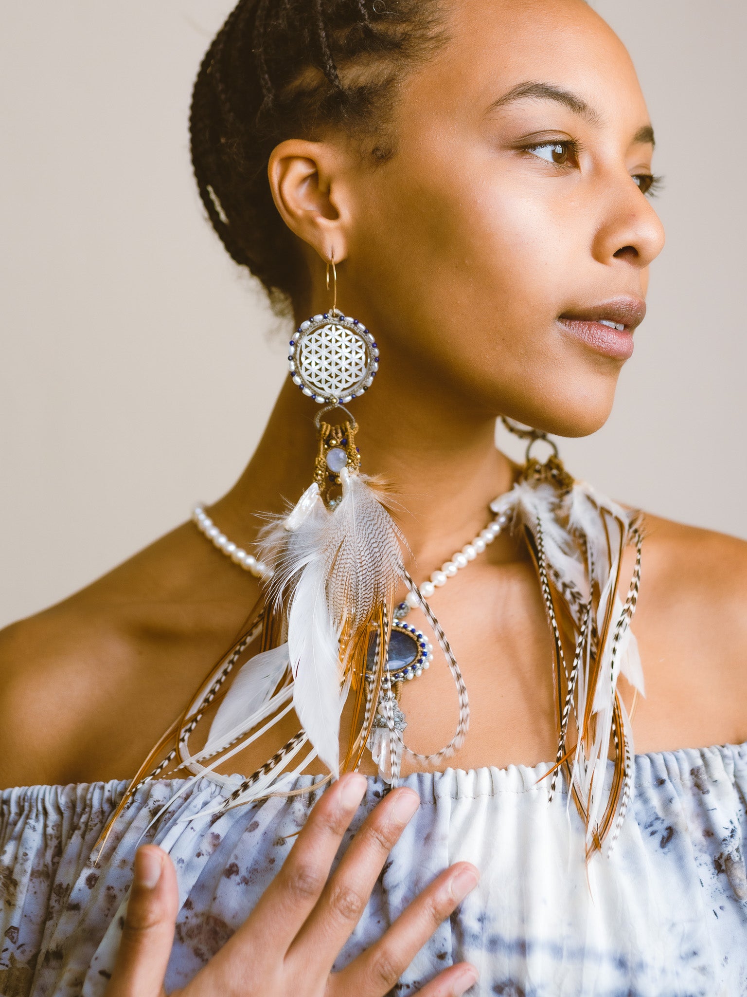 Front view of model wearing Feather Earrings – a statement piece handcrafted with Flower of Life Sacred Geometry, featuring clear quartz, Lapis, pearl & gold.