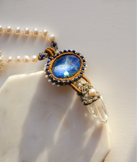 Necklace with blue gemstone and crystal pendant on a white background