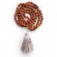 Rudraksha & Quartz 108 Meditation Mala. Handcrafted to align with your higher self, silk knots hold affirmations, enhancing your practice. Sacred Numerology adorned with healing gemstones; each piece includes a silk bag & guided meditation. Made to order for your awakening journey. Folded on a white background.