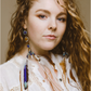 Front view of model wearing Feather Earrings – a statement piece adorned with gemstones and precious metals, including clear quartz, Lapis, pearl & gold, and cruelty-free Indian Roller feathers.
